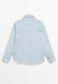 Ljusblå långärmad skjorta i mjukt tyg, med krage, knappade manschetter och en ryggdesign med yoke. Slät textur och enkel design.