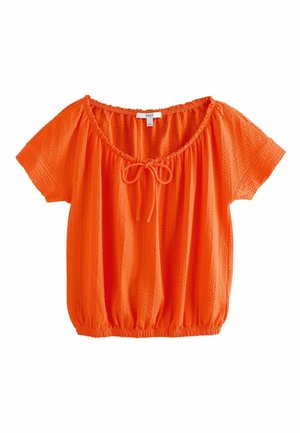 Blouse orange vif à manches courtes avec encolure élastique, détail noué à l’avant, tissu texturé et ourlet élastique.