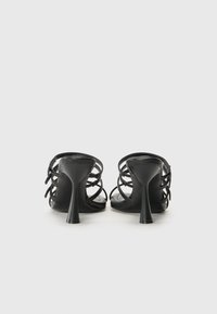 Sandales noires à talons avec un design à lanières et un talon arrondi. Texture lisse, dos ouvert et détails de lanières réglables.