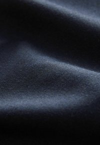 Dark blue fabric with a smooth texture, showing subtle wrinkles and light reflections that highlight its soft finish.