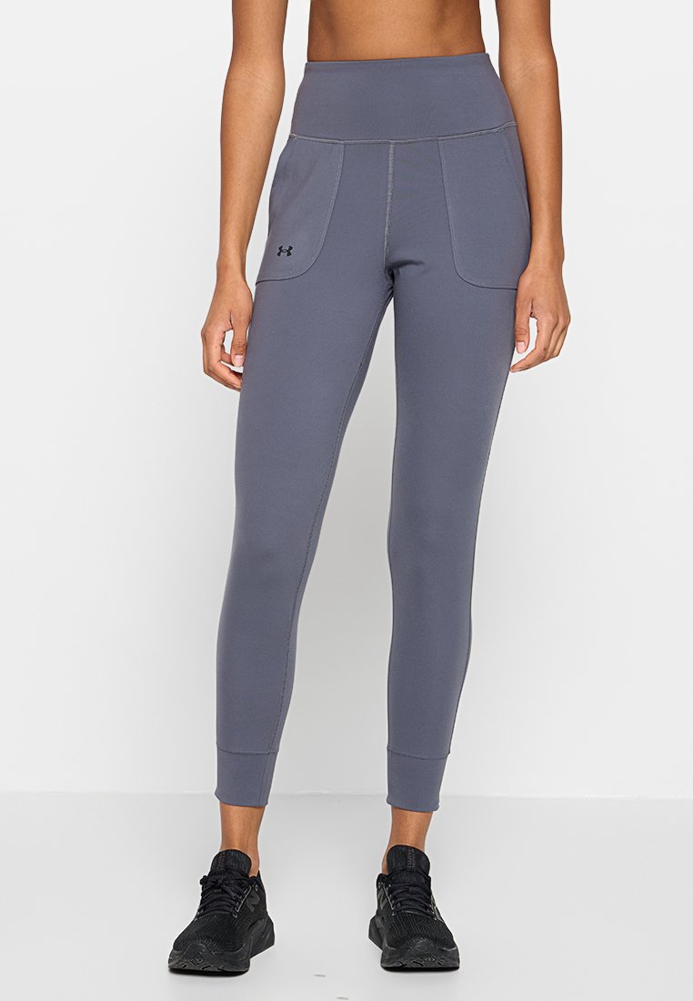 Leggings gris taille haute avec poches latérales, fabriquées en matériau extensible. Caractéristiques de surpiqûres contrastantes et d'un design ajusté.