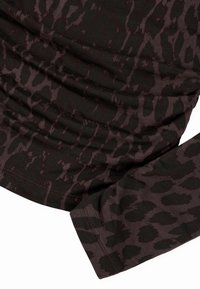 Langärmliges Oberteil aus dunkelbraunem Stoff mit dezentem Leopardenmuster, das eine geraffte Textur und kontrastierende Nähte am Saum aufweist.