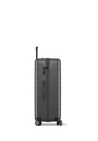 Schwarzer Hartschalenkoffer mit horizontalen Rillen, ausziehbarem Griff, TSA-Schloss und vier Rädern für Mobilität. Robustes und elegantes Design.