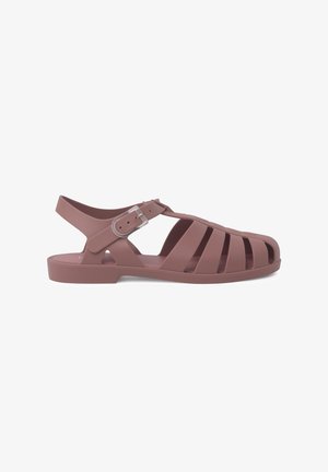Molded plastic sandals in a soft pink color with a strap and buckle, featuring cutouts for breathability and a flat sole.