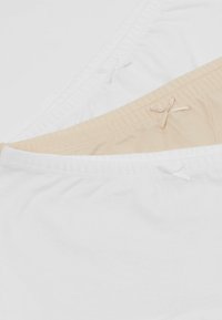 Zwei Unterwäschepaare: eines in Weiß, das andere in Nude. Beide bestehen aus einem weichen Baumwollmaterial mit einer glatten Textur und kleinenbandakzenten am Bund.