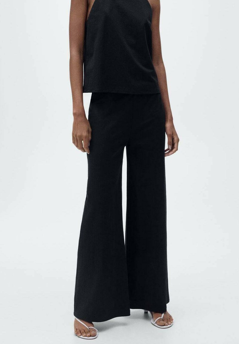 Black wide-leg pants made of lightweight material paired with a black sleeveless top. Features a relaxed fit and minimalist design.
