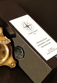 Gouden kompas met gedetailleerde gravures naast een zwarte doos met een wit etiket voor "FOURTY-FIRST®", waarin geavanceerde bodycrème zit.