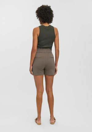 Pantaloni corti marroni con vita elastica e tasche posteriori, abbinati a una maglietta aderente senza maniche di colore verde scuro, visti da dietro. Texture liscia.