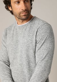 Grau gestrickter Pullover mit rundem Halsausschnitt und langen Ärmeln, der ein strukturiertes Muster und einen weißen Krageninnenbesatz aufweist.