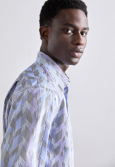 Camisa de manga larga con un patrón geométrico en tonos de azul y negro. Presenta un cuello con solapa y un acabado de tejido texturizado.