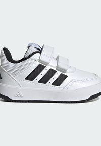 Bijela sportska cipela s crnim detaljima, s glatkim kožnim gornjim dijelom, mrežastim panelima i dvije Velcro trake. Izdržljiv gumeni potplat.