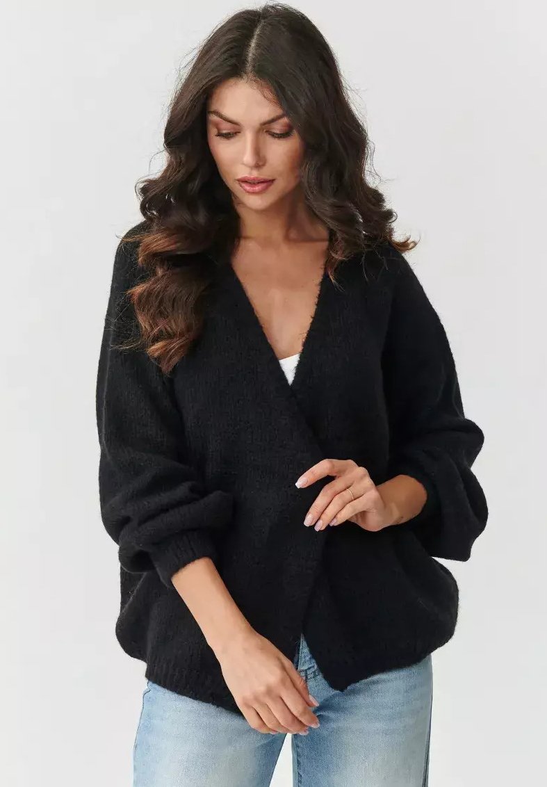 Czarny, duży kardigan o teksturowanym splocie, z głębokim dekoltem w kształcie V i obszerne rękawy. Nosi się go na białą bluzkę, w połączeniu z jasnoniebieskimi dżinsami.