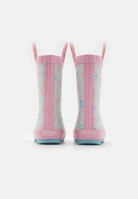Bottes de pluie en caoutchouc rose sur un fond blanc, ornées de motifs de cœurs bleus et roses, avec un talon prononcé et deux poignées de traction.