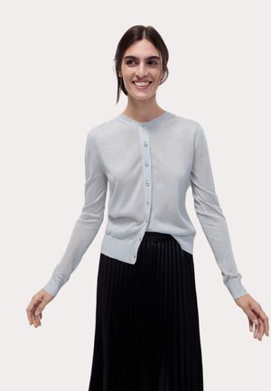 Light blue, metallic-thread cardigan with a round neckline, front button closure, and long sleeves, paired with a black pleated skirt.
