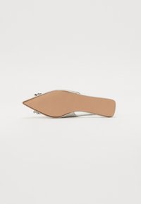 Chaussure à talon aiguille argentée avec une pointe fine, texture lisse et un accent décoratif à l'arrière. Semelle beige avec un motif de grip texturé.