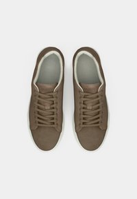 Par av brune semskede snøresko med hvite såler, sett ovenfra på en hvit bakgrunn.