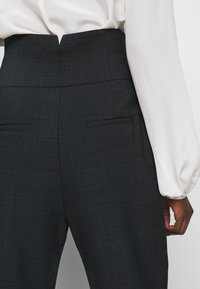 Höga rutiga byxor i mörkgrått tyg, med en slät struktur, sidofickor och en skräddarsydd silhuett.