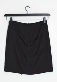 Černá sukně ke kolenům vyrobená z hladkého materiálu, která má vzadu zip a přizpůsobený pas. Visí na černém plastov ém ramínku.