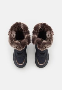 Botas de invierno azul marino con un suave puño de piel marrón, que presentan una suela texturizada negra y un sistema de cordones a juego. Material sintético.