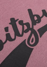 Textiel met een gestructureerde roze achtergrond met vetgedrukte zwarte cursieve letters. Het ontwerp bevat scherpe accenten en vormen voor extra nadruk.