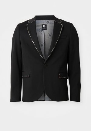 Blazer negro de tela suave, con acentos plateados con tachuelas a lo largo del cuello y los bolsillos, y un forro gris claro con patrón.