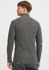 Suéter ajustado de manga larga en punto texturizado gris, con un cuello alto y puños acanalados, y un dobladillo recto en la cintura.