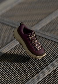Fioletowe i beżowe buty trekkingowe z teksturowaną górną częścią, wyściełanym kołnierzem, brązowymi akcentami i wzmocnionym palcem, z wyraźnym sznurowaniem i gumową podeszwą.