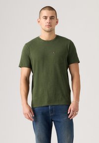 Tricou scurt cu manecă, de culoare verde măsliniu, confecționat dintr-un material moale, având un buzunar pe pieptul stâng cu un mic etichetă logo. Design clasic cu gât rotund.