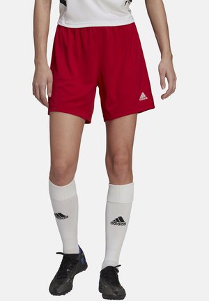 Red athletic shorts with an elastic waistband, white socks with black Adidas logo, and black cleats. Focus on comfort and performance.