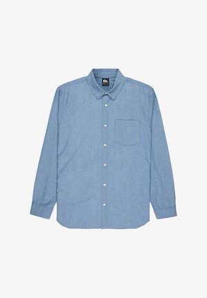 Chemise en denim bleu clair à manches longues. Elle présente un col pointu et une poche sur la poitrine gauche.