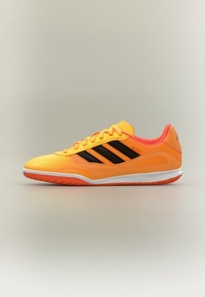 Zapatilla deportiva de color naranja brillante con rayas negras, entresuela blanca y suela naranja, mostrada de lado sobre un fondo neutro.