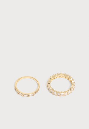 Deux bagues en or avec des pierres précieuses transparentes ; une bague a des pierres rectangulaires, l'autre a des pierres rondes tout autour de l'anneau.