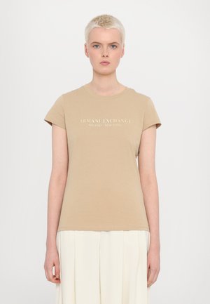 Tan cotton t-shirt with short sleeves, featuring "Armani Exchange Milano/New York" text in white across the chest. Smooth texture, classic fit.