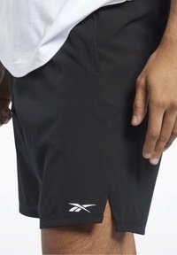 Pantaloni sportivi neri realizzati in tessuto testurizzato, con spacco laterale e dettagli del logo bianco all'orlo. Progettati per comfort e mobilità.