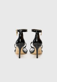 Sandales à talons hauts en cuir verni noir, dotées d'une lanière à la cheville, d'un design ouvert à l'avant et d'un talon aiguille mince avec des finitions en or.