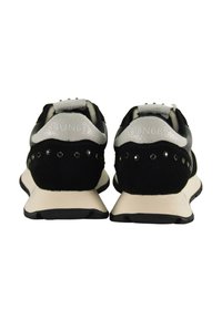Schwarze Sneakers mit grauen Akzenten, aus Wildleder und synthetischen Materialien, flacher Sohle, dekorativen Nieten und geprägt Logo auf der Rückseite.