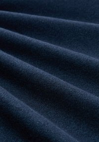 Marineblaue Stoff mit glatter Textur, der diagonale Falten aufweist, die gewebte Details offenbaren. Das Material wirkt weich mit einem subtilen Glanz.