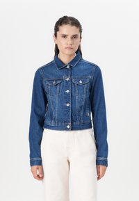 Jaqueta de ganga cropped em azul escuro, com colarinho pontudo, fecho com botões, dois bolsos no peito e detalhes cosidos ao longo das costuras.