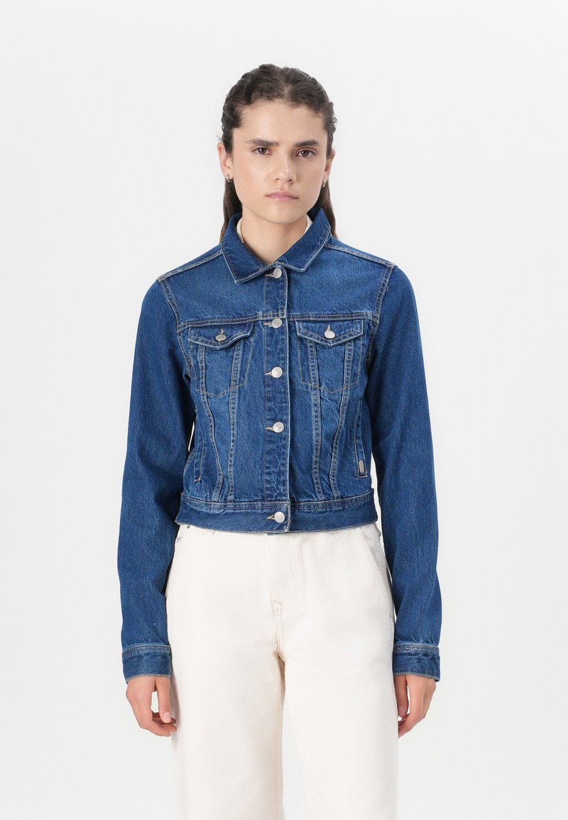 Jaqueta de ganga cropped em azul escuro, com colarinho pontudo, fecho com botões, dois bolsos no peito e detalhes cosidos ao longo das costuras.