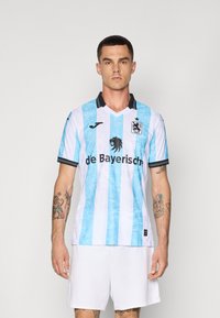 Šviesiai mėlyna ir balta dryžuota futbolo marškinėliai su juodu apykakle ir akcentais, su liūto logotipu ir užrašu "de Bayerisch". Pagaminta iš oro pralaidaus audinio.
