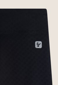 Leggings sportivi neri con un motivo testurizzato, dotati di un logo argentato sul lato sinistro e un dettaglio della cintura liscia.