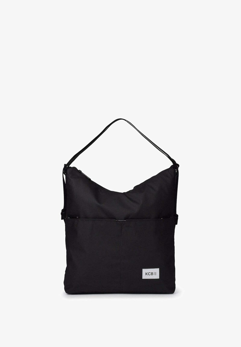 Sac à bandoulière noir rectangulaire avec une seule sangle, une poche avant et une petite étiquette logo rectangulaire portant l'inscription "KCB" dans le coin inférieur.