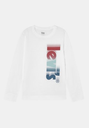 Biała koszula z długim rękawem z pionowym logo "Levi's" w kolorach czerwonym, jasnoniebieskim i ciemnoniebieskim, umieszczonym na środku z przodu.
