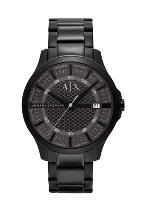 Montre en acier inoxydable noir avec un cadran texturé à motif hexagonal, des accents argentés, des aiguilles lumineuses et un affichage de la date à 3 heures.