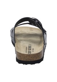 Zwarte leren sandaal met een kurken voetbed, verstelbare band en textuurvoering. Beschikt over een stevige rubberen outsole en een geperst logo op het voetbed.