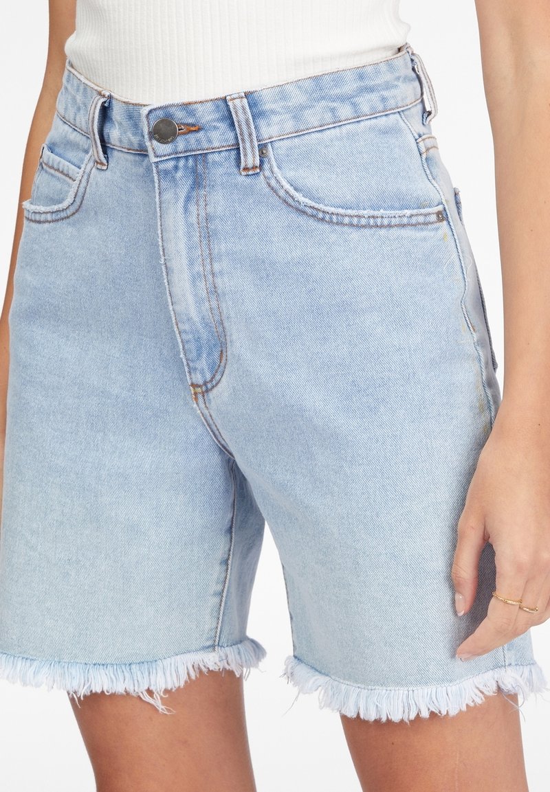 Shorts di denim azzurro chiaro con orlo sfilacciato. Design a cinque tasche, cuciture visibili e bottone in metallo in vita. Texture liscia.