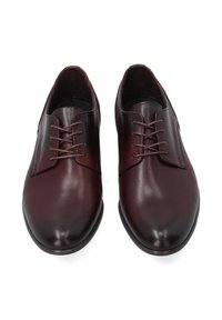Bordeaux leren schoenen met een gladde textuur, ronde neus en minimalistisch ontwerp. Voorzien van symmetrische vetersluiting met zes vetergaatjes en een platte zool.