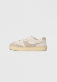 Beige and gray suede sneaker with a textured surface, lace-up design, and a thick cream sole. Features contrasting panels and stitching.