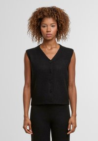 Černý bezrukávový svetr s véčkovým výstřihem a šesti černými knoflíky vpředu. Měkká textura a uvolněný střih.