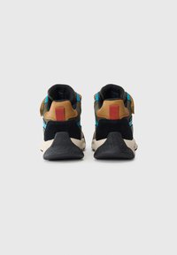 Par de zapatillas multicolores vistas desde la parte trasera con suelas negras, acentos marrones y azules, y tiradores rojos sobre un fondo blanco.